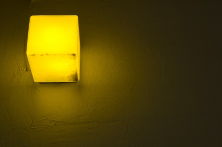 Yellow lamp light - on concrete wallの写真素材