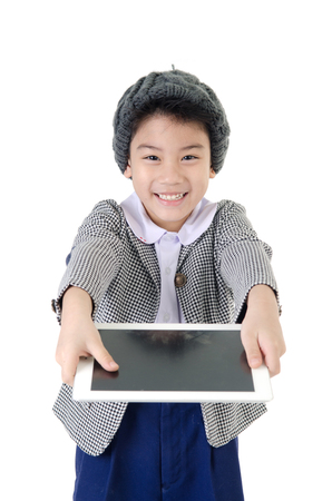 Little asian boy in student's uniform with tablet computer on isolated backgroundの写真素材