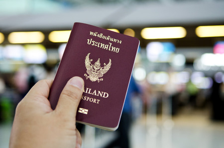 hand holding Thailand passport with gate of airport backgroundの写真素材