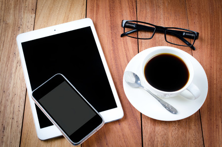 empty tablet and a cup of coffee on the wooden desk backgroundの写真素材