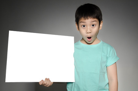 Portrait of Happy Asian boy with blank plate for add your text on gray backgroundの写真素材