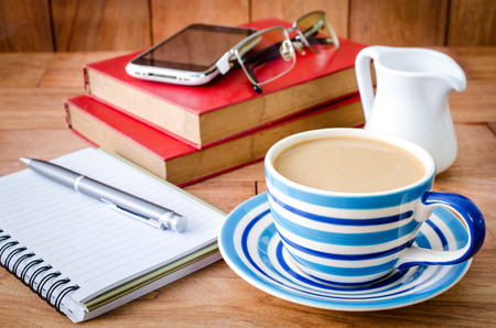 cup of coffee on the office desk with note book . の写真素材