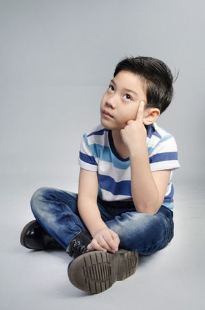 Portrait of little asian cute boy acting think about that on gray background .の写真素材