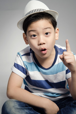 Portrait of little asian cute boy with whit hat on gray background .の写真素材