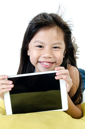 Little asian girl smiles with tablet computer on white background . の写真素材