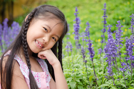 Asian little girl squat in flowers  in the  parkの写真素材