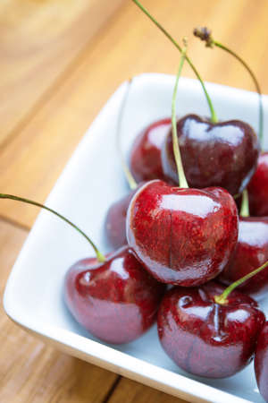 Fresh red Cherries on wooden table with water drops macro background