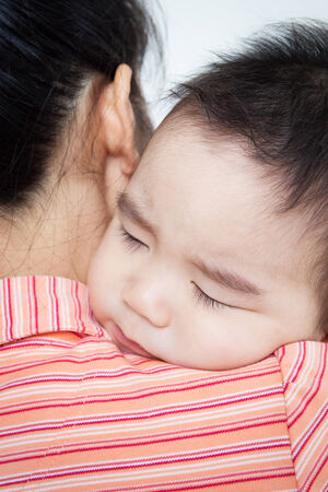 Asian baby boy sleeping on hand with your mom .の写真素材