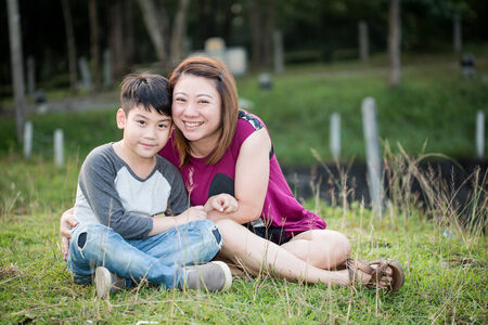 Son hugging mother Asian family in the parkの写真素材