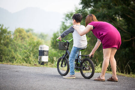 little Asian child with mother practice to riding a bicycle at the parkの写真素材