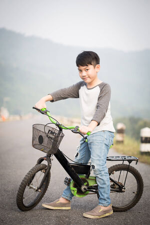 Asian cute boy riding on his bycicle on the roadの写真素材