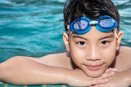 Portrait of happy asian little boy playing in the pool