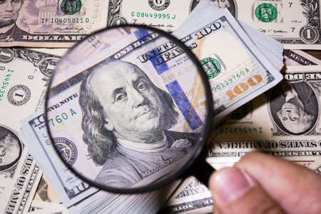 magnifying glass lies on american dollars on bank note backgroundの写真素材