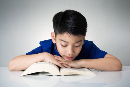 Little asian boy read a book on gray background