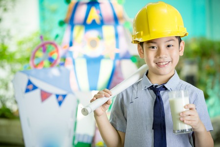 Young asian child construction engineer holding a glass of milkの写真素材