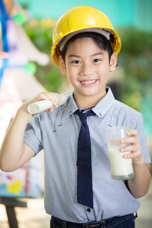 Young asian child construction engineer holding a glass of milkの写真素材