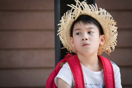 Asian bored child with red backpack is thinking whileの写真素材