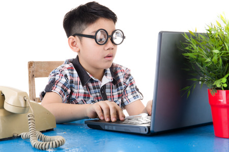 Little asian boy with eye glasses using his laptop