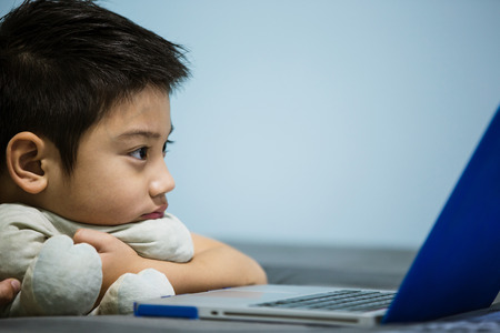 Little Asian Child watching screen Laptop At Home