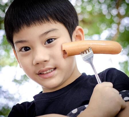Asian cute Child eating a sausageの写真素材
