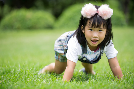 Little asian girl playing on green grass at the par
