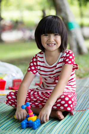 Portrait of asian girl in the park sitting on green plastic mat with toyの写真素材