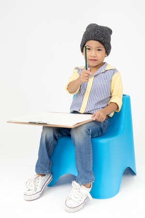 Happy Asian little artist boy holding a blank art board  on gray background