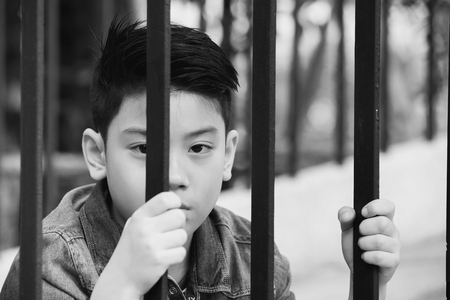 asian boy behind iron bars ,Black and white toneの写真素材