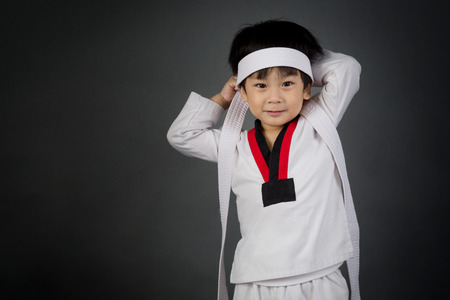 Asian cute child training in TAEKHONDO uniform on gray backgroundの写真素材