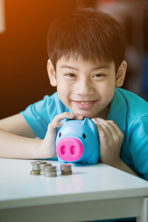 Little asian boy insert coin into piggy bank with smile face.の写真素材