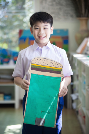 Happy asian child show his craft and looking camera at kindergartenの写真素材