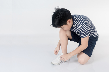 Portrait asian child trying to put his shoes on gray backgroundの写真素材