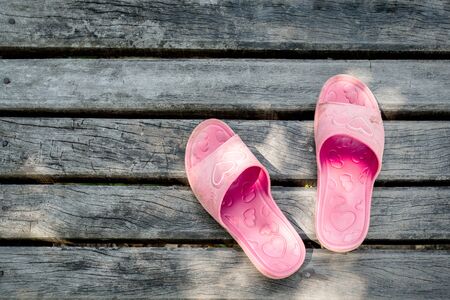 Old pink sandal on wood plate texture backgroundの写真素材