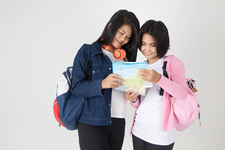 tourism, travel, leisure, concept - smiling teenage girls with map and laptop on gray backgroundの写真素材
