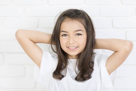 Headshot Portrait of happy cute girl smiling looking at camera. White wall background.
