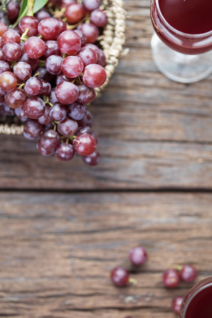 Glass of wine or grape juice and fruit on wooden table near glass windowの写真素材