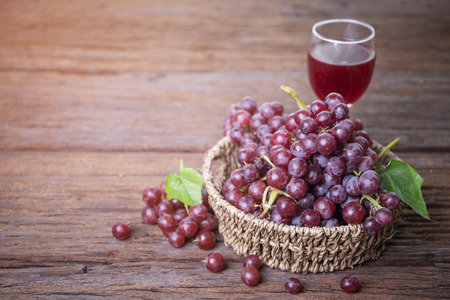 Glass of wine or grape juice and fruit on wooden table near glass windowの写真素材