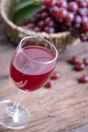 Glass of wine or grape juice and fruit on wooden table .の写真素材