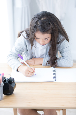 Cute Asia girl writing something in paper with colour pencils,Drawing at home creativity development .の写真素材