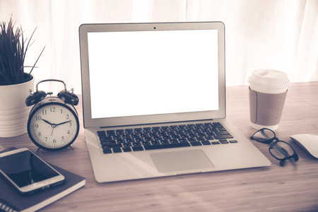 Laptop with smart phone notebook and coffee cup on workplace table.White background on laptop screen for ad your text.の写真素材