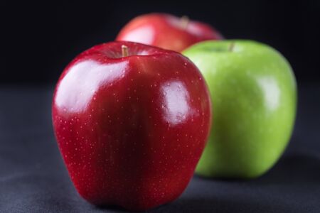 Different kinds of apples and the tasty benefits of each. Green and red of apples on black...
