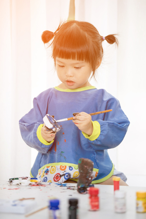 Portrait of a cute little girl messily playing with paints.の写真素材