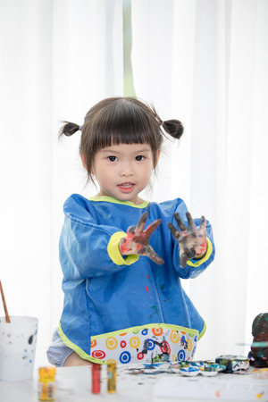 Portrait of a cute little girl messily playing with paints.の写真素材