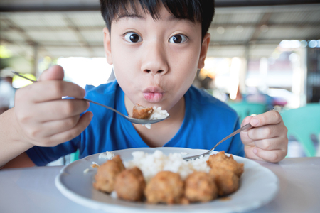 Asian cute boy eat breakfast and looking camera with smile face .の写真素材
