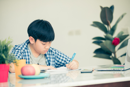 Thinking child bored, frustrated and fed up doing his homework.の写真素材
