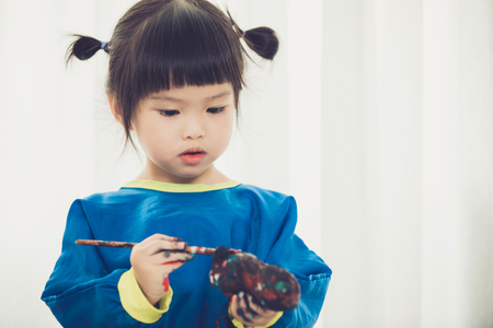 Portrait of a cute little girl messily playing with paints.の写真素材