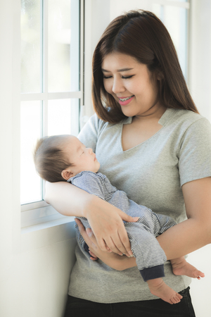 Proud asian mother holding his baby son in his at home.の写真素材