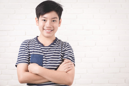 Portrait of asian cute boy and good looking with smile on white brick wall background.の写真素材