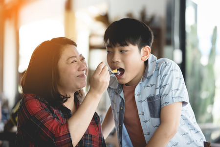 Young beautiful mother feeding her son.の写真素材