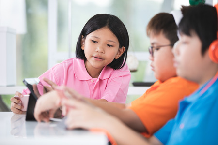 Asian child playing tablet computer togetherの写真素材